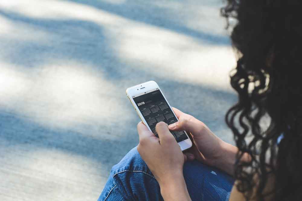 Mujer sosteniendo un teléfono inteligente con la aplicación de diario.