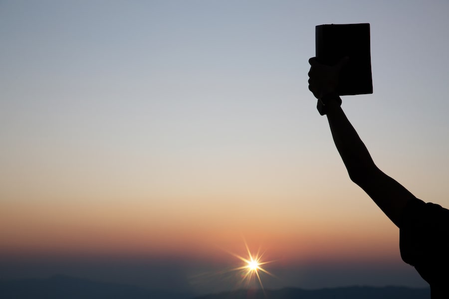 Un creyente en Cristo sosteniendo un diario de la Biblia con afirmación.