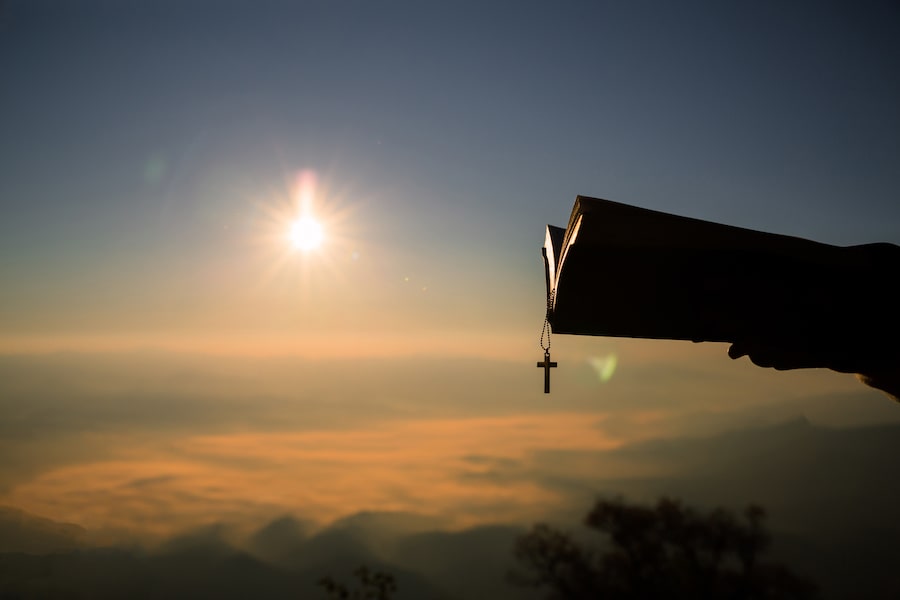 Ein Mann liest eine heilige Bibel auf einem Berggipfel.