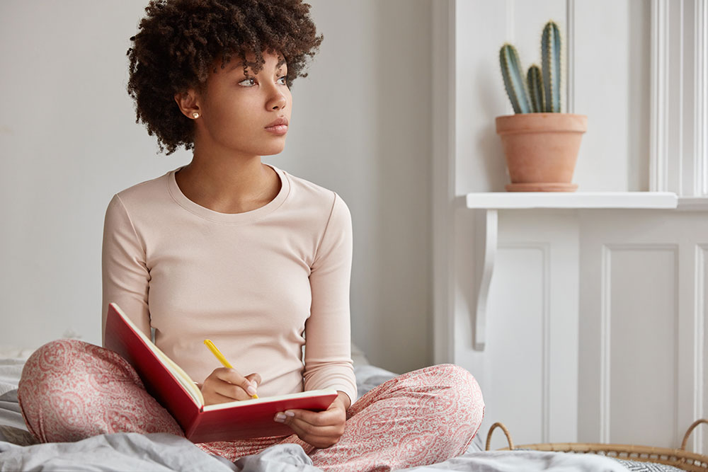 Une jeune fille tenenant un journal sur son lit.